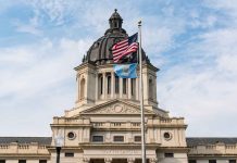 Building with dome and flags flying outside.