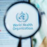 Magnifying glass focused on World Health Organization logo.