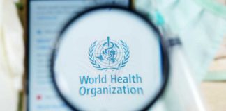 Magnifying glass focused on World Health Organization logo.