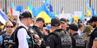 Police officers gathered near a crowd with flags.