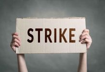 Two hands holding a cardboard sign saying "STRIKE".