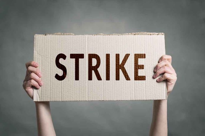 Two hands holding a cardboard sign saying "STRIKE".