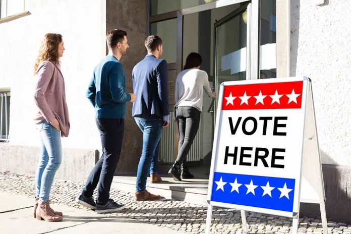 People entering building with "Vote Here" sign nearby.