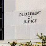 Department of Justice building exterior with window and plants.