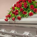 Casket adorned with a bouquet of red roses.