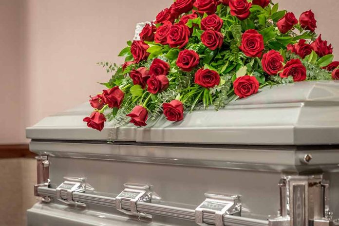 Casket adorned with a bouquet of red roses.