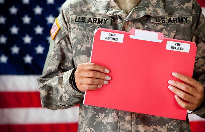 Soldier holding red top secret file folder.