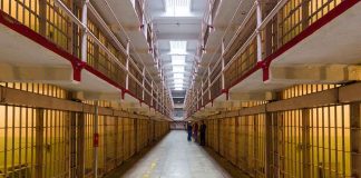 Long hallway with prison cells on both sides.