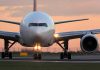 Airplane on runway during sunset, lights on.