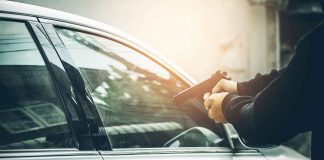 Person pointing gun at a car window