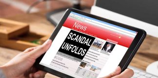 Person holding tablet displaying news headline Scandal Unfolds