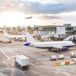 Airport with airplanes, runway, and terminal at sunset