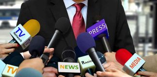 Person surrounded by microphones from various media.