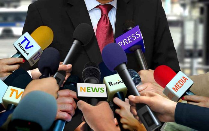 Person surrounded by microphones from various media.