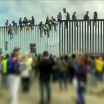 People sitting on high metal fence during protest.