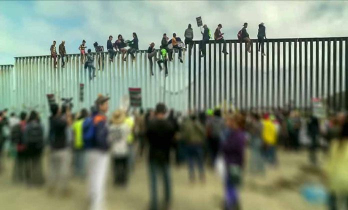 People sitting on high metal fence during protest.