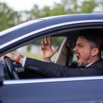 Man yelling inside a car, looking frustrated