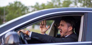 Man yelling inside a car, looking frustrated