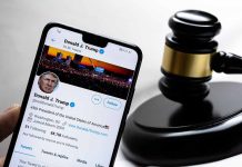 Smartphone displaying Twitter profile beside a judge’s gavel