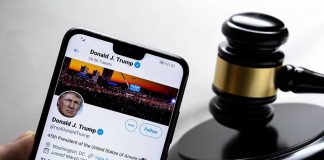 Smartphone displaying Twitter profile beside a judge’s gavel