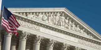 US Supreme Court building facade with flag.