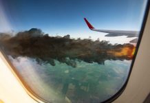 Airplane wing with engine on fire mid-flight.