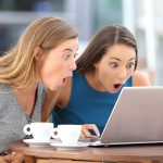 Two women surprised while looking at a laptop