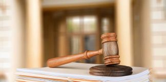 Gavel resting on stack of paperwork in courtroom