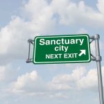 Green sign saying Sanctuary City Next Exit.