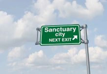 Green sign saying Sanctuary City Next Exit.