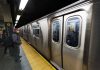 Man waiting at subway platform with departing train.