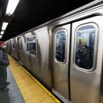 Man waiting at subway platform with departing train.