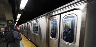 Man waiting at subway platform with departing train.