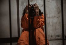 Person sitting in jail cell wearing orange jumpsuit