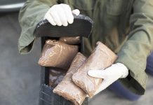 Person handling packages wearing gloves and green jacket