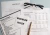 Documents and glasses on table with "Minimum Wage" paper