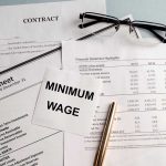 Documents and glasses on table with "Minimum Wage" paper