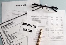 Documents and glasses on table with "Minimum Wage" paper