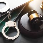 Gavel, handcuffs, and books on a table.