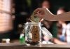 Hand placing dollar bill into a tip jar.