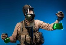 Scientist in hazmat suit holds green liquid samples