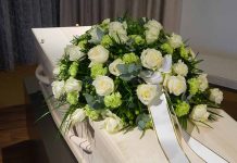 White roses on a coffin with ribbon.