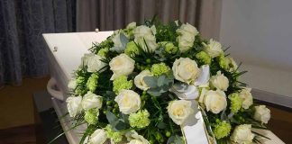 White roses on a coffin with ribbon.