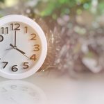 White analog clock with blurred green background