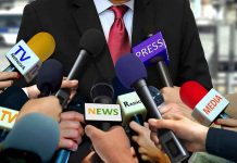 Person surrounded by microphones from various media