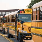 School buses lined up in front of building.