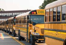 School buses lined up in front of building.