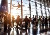 Passengers waiting at airport gate with airplane outside window.