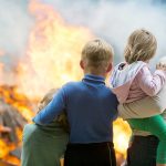 People watching large outdoor fire together