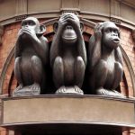 Three wise monkeys statue on a brick building.